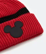 Gorro de tejido acanalado color rojo con una franja horizontal negra. Presenta un parche de goma negro con la silueta de la cabeza de Mickey Mouse en la parte frontal.