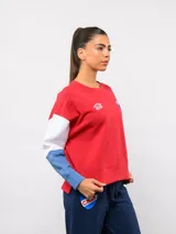 Buzo de cuello redondo con diseño de bloques de color en rojo, blanco y azul. Presenta el logo de Umbro y el escudo del Club Nacional de Football bordados en el pecho.