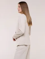 Blazer de sastrería color beige, sin solapas, con cuello en V profundo y cierre frontal de un único botón circular metálico en contraste.