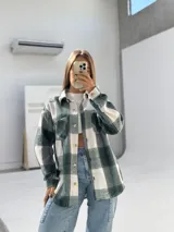 Camisa de paño a cuadros grandes en tonos verde y blanco, con cuello clásico, cierre frontal con botones y bolsillo en el pecho.