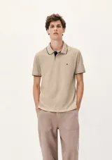 Chomba de manga corta color negro con cuello y tapeta interior en color gris claro. Presenta un pequeño bordado en el pecho y detalles de ribete en gris en el cuello y las mangas.