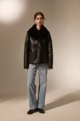 Chaqueta de eco-cuero color beige con interior y cuello de piel sintética al tono. Presenta un diseño holgado, cierre frontal con un botón y solapas amplias.