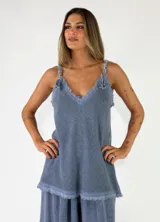 Top de lino y algodón color azul, de corte holgado, con escote en V y detalles de flecos en los bordes y tirantes.