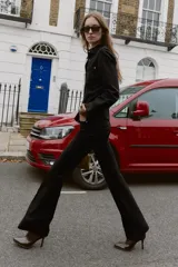 Pantalón flare de tiro bajo color marrón oscuro, con bolsillos delanteros y traseros, pierna entallada y bajo acampanado. Cierre frontal con cremallera y botón.