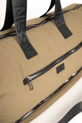 Bolso de gran capacidad color beige, con asas fijas superiores y correa de cinta negra desmontable y regulable. Presenta un bolsillo externo con cierre, un compartimento inferior con cierre y logo de la marca Daniel Cassin en el frente.