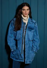 Parka de jean oversize con acabado lavado, cuello clásico, bolsillos frontales con tapa y cierre frontal. Presenta un diseño de silueta amplia y relajada con puños regulables.