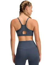 Top deportivo Under Armour Infinity Low 2.0 de color azul grisáceo, diseñado para ofrecer soporte estratégico en actividades de bajo impacto. Cuenta con escote redondo, tirantes ajustables y paneles traseros de malla para mayor transpirabilidad.