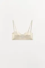 Sujetador de color blanco hueso o crema, con aros y copas moldeadas, corte recto en el bajo y tirantes finos ajustables y extraíbles.