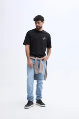 Remera oversize Brooksfield de color negro, confeccionada en 100% algodón, de manga corta y corte relajado. Cuenta con un diseño estampado en relieve en la espalda que representa flores abstractas y texto descriptivo en tono verde militar.