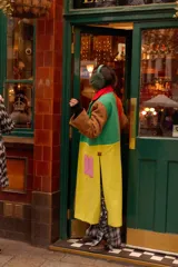 Tapado largo de paño con diseño color block en tonos marrón, verde, amarillo y naranja. Presenta solapas, bolsillos de parche en contraste rosa y un corte recto.