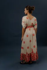 Vestido largo beige con estampado paisley en color azul marino, escote en V profundo con detalle bordado, mangas cortas amplias, cordón ajustable en la cintura con borlas y volados en el ruedo.