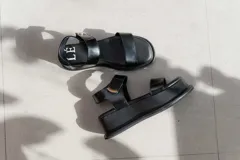 Sandalias de plataforma color negro, con diseño de dos tiras anchas en el empeine y cierre con velcro en el tobillo. Presentan una suela de plataforma alta y liviana.