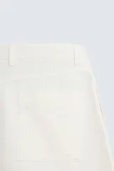 Bermuda de corte regular fit, color blanco hueso, confeccionada en tejido de algodón y lino. Presenta pliegues frontales, bolsillos delanteros y bolsillos traseros de plastrón.