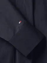 Camisa azul marino de algodón orgánico con corte amplio, cuello inglés, cierre frontal con botones blancos y logo de Tommy Hilfiger bordado en la manga.
