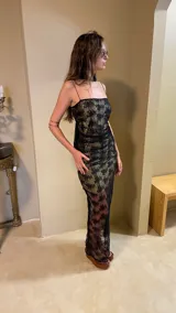 Vestido largo negro con estampado dorado, de breteles finos y corte ajustado.