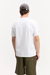 Remera blanca de manga corta y cuello redondo, confeccionada en algodón, con estampa frontal geométrica y tipográfica multicolor.
