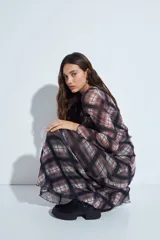 Falda larga de corte fluido con estampado de cuadros en tonos oscuros, rojizos y blancos. Presenta un diseño ligero con terminaciones onduladas en el ruedo.