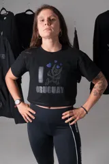 Crop top negro de algodón elastizado con estampado frontal que incluye la frase 'I ❤️ URUGUAY' y un dibujo de un personaje alado.