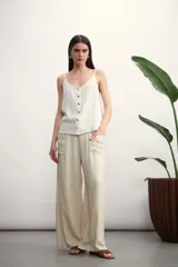 Pantalón de corte ancho y tiro alto, confeccionado en tejido de textura natural. Presenta cintura elástica con cordón ajustable, bolsillos laterales tipo parche y diseño de pierna recta y holgada.