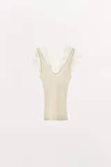 Top de punto acanalado en color beige, con escote en pico y tirantes anchos decorados con aplicaciones de encaje a tono.