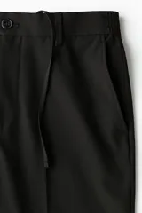 Pantalón de corte relajado color negro, con cintura elástica, cierre frontal con botón y cordón de ajuste oculto. Presenta piernas con raya marcada, bolsillos laterales al bies y bolsillos traseros ribeteados con botón.