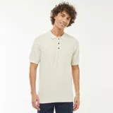 Remera polo de manga corta color crema, de punto con textura en zigzag y cuello clásico con tres botones.
