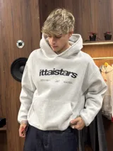 Hoodie gris jaspeado con capucha, bolsillo frontal tipo canguro y estampado gráfico en el pecho con la marca ittaistars.
