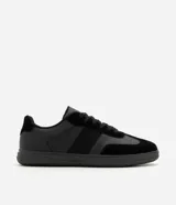 Championes urbanos para hombre en color negro, con diseño monocromático de perfil bajo. Combinan inserciones de material sintético y textura tipo gamuza en la puntera y laterales, con cierre de cordones al tono.