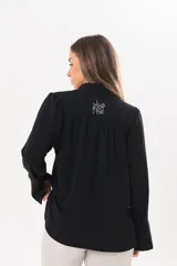 Camisa de manga larga color negro, de cuello redondo con frunces, abotonada en el frente y puños abiertos con tajo.