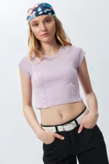 Top corto de manga corta, color negro con efecto desgastado o acid wash, cuello redondo y costuras verticales que definen la silueta.