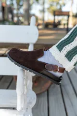 Zuecos de cuero marrón con talón descubierto y suela de goma.