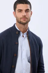 Cardigan de punto grueso color azul marino, con cuello alto, cierre frontal de botones marrones y ribetes marrones en el interior.