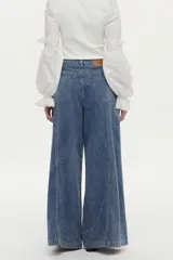 Pantalón jean de pierna ancha con calce relajado y detalles de costuras decorativas verticales en el frente, color azul.