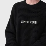 Sweater de punto acanalado en color negro, con cuello redondo y diseño de corte holgado. Presenta el nombre de la marca bordado en el centro del pecho en color blanco.
