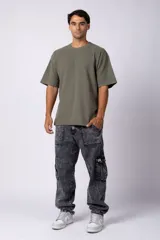 Remera de corte oversized en color marrón, confeccionada en tejido de algodón con textura de micropanal. Presenta cuello redondo con detalle de costura en forma de X y mangas cortas de estilo caído.