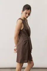 Vestido corto blanco sin mangas, con cuello redondo y detalle de nudo drapeado en el lateral.