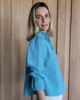 Blusa de algodón con cuello mao y volados, mangas largas con puños elásticos y corte holgado.