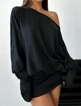 Vestido corto negro elastizado, asimétrico, de manga larga y hombro al descubierto.