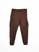 Pantalón de jogging tipo cargo color marrón, con cintura elástica ajustable con cordón, bolsillos laterales con solapa y puños elásticos en los tobillos. Presenta un pequeño estampado con texto en el muslo.