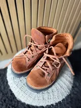 Botas Saura de cuero y gamuza en color tostado, con cordones frontales, suela gruesa y diseño tipo borceguí.