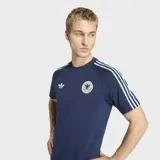 Remera Adidas de la selección de Alemania, línea Originals, color azul marino. Presenta cuello redondo, mangas cortas con las tres tiras características en celeste, logo del Trifolio en el pecho derecho y escudo de la federación alemana en el pecho izquierdo.