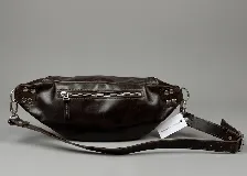 Riñonera de cuero color negro, con múltiples compartimentos con cierre metálico, detalles de tachas en los laterales y correa regulable.