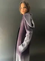 Tapado largo de lana merino color gris oscuro con teñido degradado en gris claro en ruedo, mangas y capucha. Tiene corte recto, bolsillos laterales y cierre cruzado con broches a presión ocultos en los hombros.