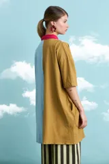 Túnica de algodón con diseño de rayas verticales multicolor en tonos celeste, marrón y fucsia. Presenta cuello polo, manga corta y cierre frontal con botones.