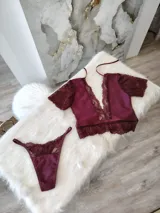 Conjunto de lencería compuesto por un top de escote profundo con detalles de encaje y mangas cortas, y una tanga regulable a juego. Confeccionado en lycra, microtul y encaje elastizado.