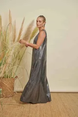 Vestido largo de corte amplio y línea simple, confeccionado en tejido de jersey con acabado metalizado plateado. Presenta cuello redondo y diseño sin mangas.