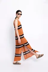 Vestido largo tejido de algodón color terracota con rayas horizontales negras y blancas. Presenta aberturas laterales en el ruedo y corte sin mangas.