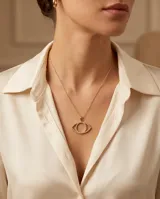 Collar de acero con baño de oro, compuesto por una cadena fina y un dije en forma de ojo con relieve adornado con circonias.