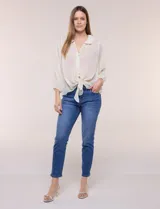 Blusa confeccionada en gasa semitransparente con sutil acabado plisado y estampado floral en tonos suaves. Presenta cuello solapa redondeado, escote en V y botonadura frontal. Mangas largas con puños elásticos y ruedo anudado en la parte inferior frontal.