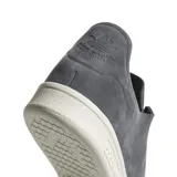 Championes Adidas modelo Stan Smith Nuud, color gris con acabado en gamuza. Presentan un diseño minimalista con suela de goma en color crema y detalles internos en tono rojizo.